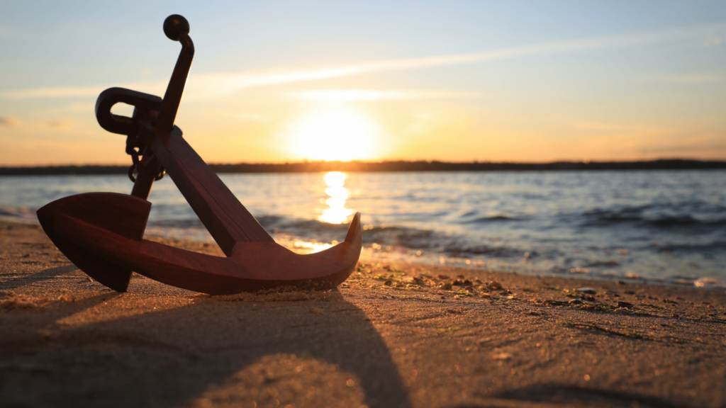 Anchor laying on the beach during sunset